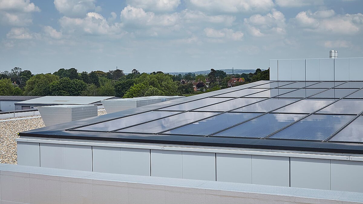Modernes Glasdach der Gewerbeimmobilie in Milton Park, England, mit reflektierender Oberfläche und bewölktem Himmel im Hintergrund.