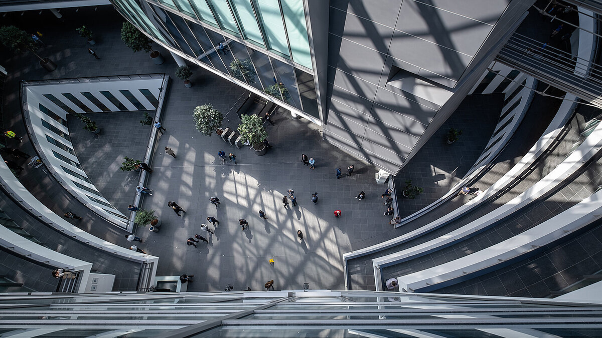 Blick in das lichtdurchflutete Atrium des BMW Group Forschungs- und Innovationszentrums (FIZ) mit moderner Architektur und geschäftiger Atmosphäre.