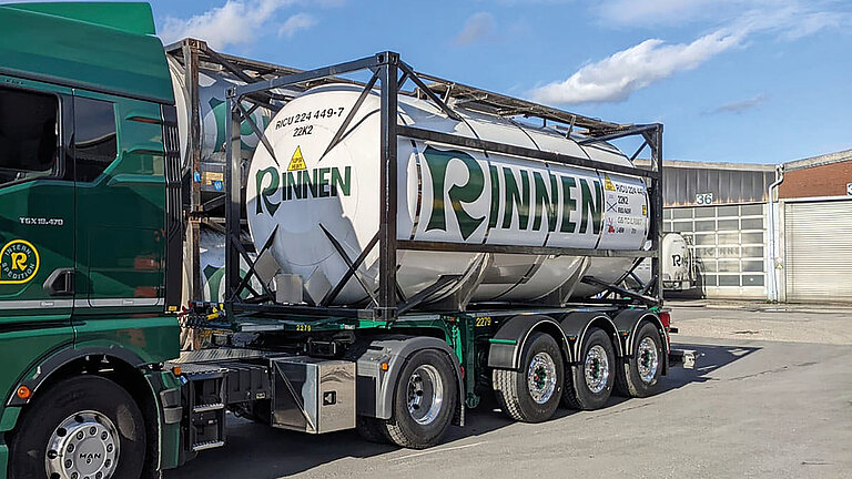 Weißer ISO-Tankcontainer auf einem grünen LKW mit der Aufschrift "RINNEN" mit GFK-Tankverkleidung