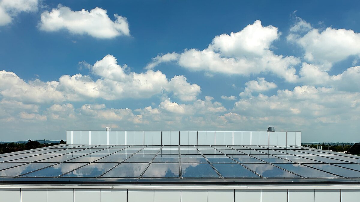 Glasdach einer modernen Gewerbeimmobilie in Milton Park, England, spiegelt den blauen Himmel mit weißen Wolken.