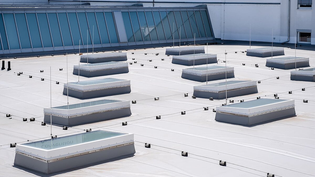 Flachdach des Vogel-Convention-Centers in Würzburg mit mehreren Flachdach-Fenstern und Glasdach-Elementen im Hintergrund.